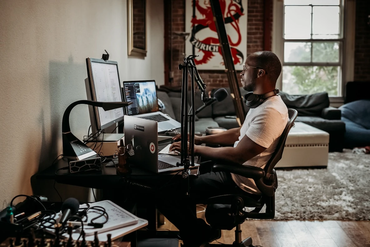 Person working at a desk with monitors and a microphone